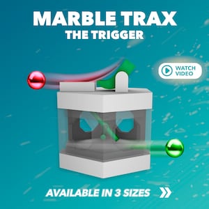 Könnte beinhalten: Ein weißer Murmelbahn-Apparat mit einer durchsichtigen Plastikbox und einer grünen und roten Murmel. Der Apparat ist mit "Marble Trax The Trigger" und "Erhältlich in 3 Größen" beschriftet.