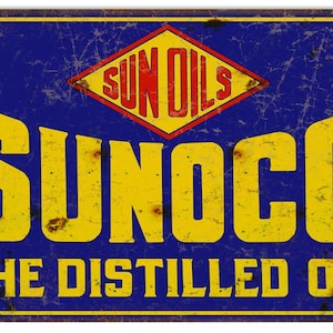 May include: Vintage metal sign with a blue background and yellow text. The sign reads "SUNOCO THE DISTILLED OIL" with a diamond-shaped logo in the top center that reads "SUN OILS" in red letters.