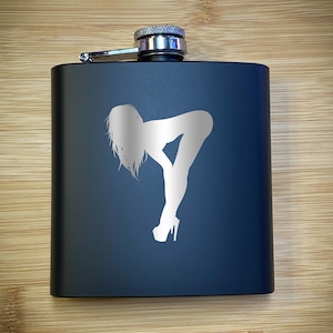 May include: A black metal flask with a silver cap and a white silhouette of a woman in a suggestive pose.