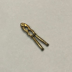 May include: A gold-colored nutcracker with a decorative design. The nutcracker is made of metal and has a hinged jaw.