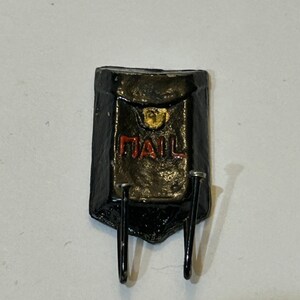 May include: Black metal mailbox with the word "MAIL" in red lettering. The mailbox has two hooks on the bottom.