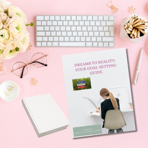 May include: A white cover with the text "Dreams to Reality: Your Goal-Setting Guide" and a photo of a person writing in a notebook. The cover is created by "Tanya & Melanie Galvin".