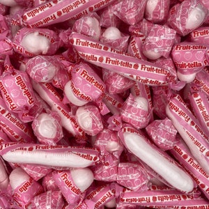 May include: A close-up of a pile of pink and white candy-coated chocolates wrapped in pink foil with the text "Fruit-tella" printed on the wrappers.