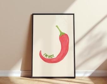May include: Framed art print showing a red chilli pepper with a green stem and the text "I'M HOT" in green. The artwork is set against a cream background and framed in a black frame.