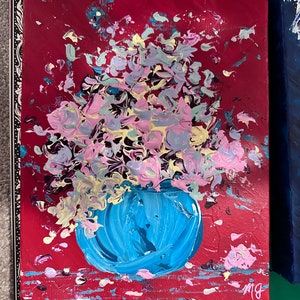 May include: A painting of a blue vase filled with pink, yellow, and blue flowers on a red background. The vase is painted with thick brushstrokes and the flowers are abstract.