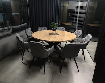May include: A modern dining set featuring a round wooden table surrounded by eight gray upholstered chairs with black metal legs. A small plant in a black pot sits in the center of the table. The room has dark gray curtains and a large window.