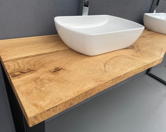 May include: A bathroom vanity with a natural wood countertop and two white square sinks. The countertop has a live edge design and is supported by a black metal frame. The sinks are made of white ceramic.