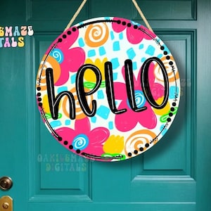 May include: A round wooden door hanger with a white background and colorful abstract floral designs. The word "hello" is written in black letters on the door hanger.