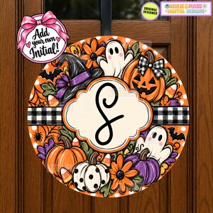 May include: A round Halloween door sign featuring a central cream-colored scalloped plaque with a black letter S. The design includes orange and white pumpkins, ghosts, a witch hat, flowers, candy corn, and a black and white buffalo plaid stripe.