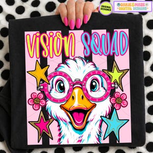 May include: Black t-shirt with a cartoon duck wearing pink glasses and the text "VISION SQUAD" in yellow and blue. The design includes stars and flowers on a pink striped background.