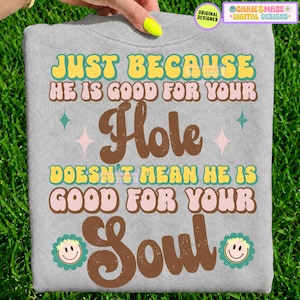 Puede incluir: Una camiseta gris claro con el texto "JUST BECAUSE HE IS GOOD FOR YOUR Hole DOESN'T MEAN HE IS GOOD FOR YOUR Soul" en letras retro amarillas, rosas y marrones, decorada con pequeñas estrellas y dos iconos de flores sonrientes.