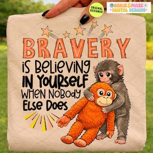 May include: A beige tote bag featuring a cartoon illustration of two monkeys hugging. The text "BRAVERY is Believing IN YOURSELF WHEN NOBODY Else Does" is written in orange and black. The design includes star and sunburst graphics.