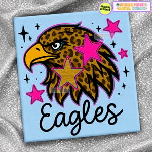 May include: A light blue square graphic featuring a leopard print eagle head with a yellow beak, surrounded by bright pink stars and small black star icons. The word Eagles is written in a black cursive script font at the bottom of the design.