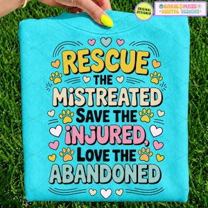 May include: A bright turquoise sweatshirt featuring a colourful graphic with the text RESCUE THE MISTREATED, SAVE THE INJURED, LOVE THE ABANDONED. The design includes yellow, pink, and light blue lettering, small paw prints, and heart icons.