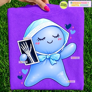 May include: A vibrant purple t-shirt featuring a graphic of a light blue, rounded character wearing a white bonnet and a bow tie. The character has closed eyes and holds an X-ray image of a human hand. Small blue hearts surround the character.