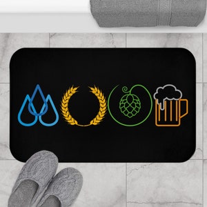 May include: Black bath mat with a design of four icons: three blue water drops, a yellow wheat wreath, a green hop, and an orange beer mug.