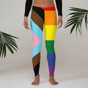 Op de afbeelding: Een zwarte legging met een diagonaal patroon van bruin, roze, blauw en lichtblauw op het linkerbeen. Het rechterbeen heeft een regenboogstrepenpatroon met rode, oranje, gele, groene, blauwe en paarse strepen.