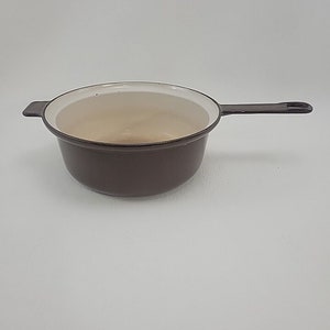 May include: A brown enameled cast iron saucepan with a white interior and a single handle.