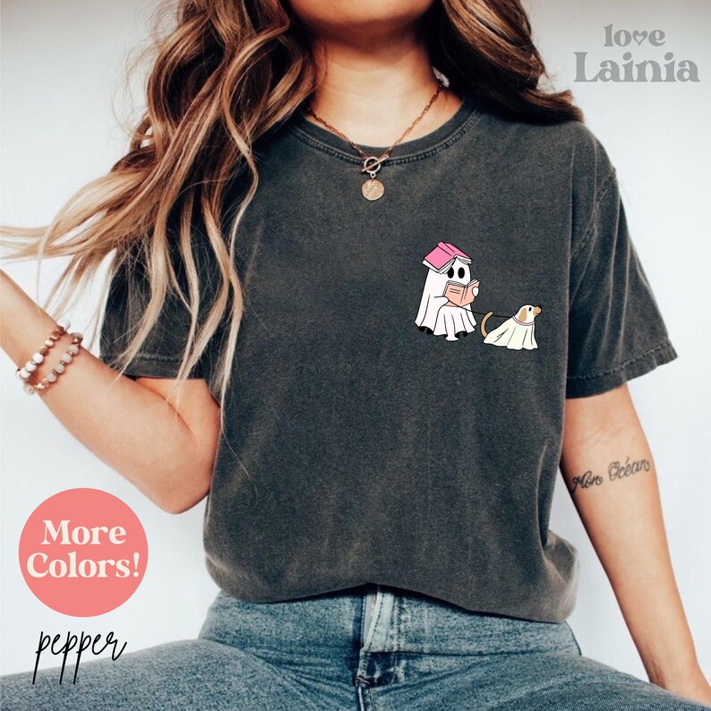 Op de afbeelding: Donkergrijs t-shirt met een afbeelding van een spook dat een boek leest en een hond met een spookkostuum. De tekst "love Lainia" staat in de rechterbovenhoek. De tekst "More Colors!" en "pepper" staan in de linkerbenedenhoek.