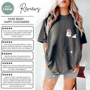 Op de afbeelding: Donkergrijs T-shirt met een cartoonafbeelding van een spook en een hond. Het shirt heeft de tekst "Reviews" en "Over 9000+ Happy Customers". De persoon draagt een grijze short.