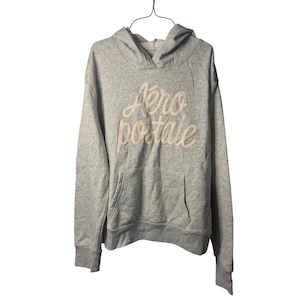 May include: A gray hoodie with a kangaroo pocket and a drawstring hood. The words "Aero postale" are embroidered in a cream-colored script across the chest. The hoodie is hanging from a wire hanger.