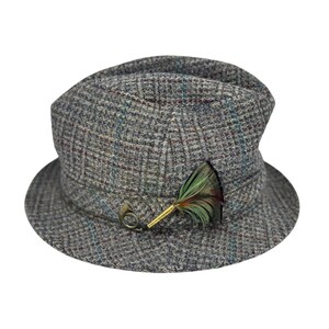 May include: A gray tweed hat with a small brim and a decorative feather and metal pin. The hat has a plaid pattern with hints of blue and brown. The feather is green and red.