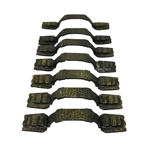 May include: A stack of seven antique bronze cabinet pulls. Each pull has a hammered texture and a curved handle. The pulls are rectangular with decorative detailing on the ends. The hardware is a dark, aged bronze color.