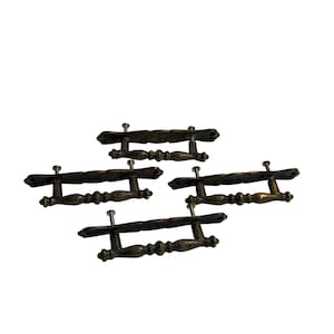 May include: Four antique bronze door handles with decorative detailing. Each handle has a rectangular backplate and a curved, ornate grip. The handles are mounted with silver screws, suggesting they are ready for installation.