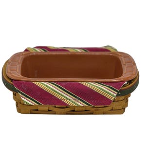 May include: A rectangular basket with a brown interior and a red and green striped fabric lining. The basket has a woven exterior and a brown rim. The fabric lining is visible around the edges of the basket.