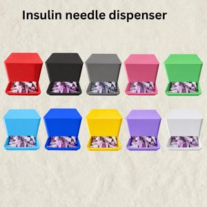 May include: A collection of ten insulin needle dispensers in various solid colors including red, black, gray, pink, green, light blue, dark blue, yellow, purple, and white. Each square-shaped dispenser features a tray filled with needles.