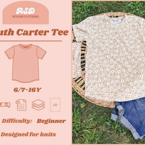 May include: A beige floral print youth tee shirt with short sleeves, paired with denim shorts, rests on a woven mat. The image includes a graphic with the text "Youth Carter Tee", "6/7-16Y", and "Difficulty: Beginner".