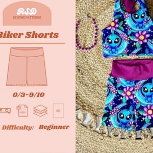 May include: A sewing pattern for biker shorts labeled RSD Sewing Patterns, 0/3-9/10, and Difficulty: Beginner. The image displays a matching crop top and shorts set featuring a dark blue fabric with a repeating pattern of blue aliens and purple flowers.