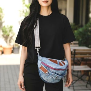Peut inclure: Un sac banane en jean avec des empiècements en cuir marron et une fermeture éclair rose. Le sac a une bandoulière à motifs et un fermoir argenté. Le sac est porté en bandoulière.
