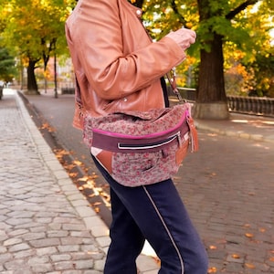 Peut inclure: Un sac à bandoulière à imprimé floral avec un accent en cuir marron et une fermeture éclair rose. Le sac a une sangle en cuir marron et une petite poche sur le devant.