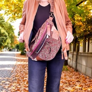 Peut inclure: Sac bandoulière marron à imprimé floral avec fermeture éclair rose et détails en cuir marron. Le sac est porté en bandoulière. Il possède une sangle en cuir marron et une étiquette en cuir marron.