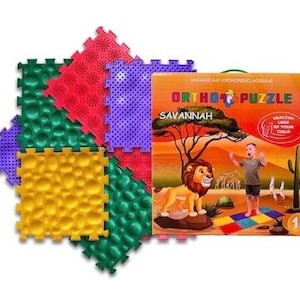 May include: A set of modular orthopedic puzzle floor mats in red, green, yellow, and purple with textured surfaces, accompanied by a rectangular product box labeled Ortho Puzzle Savannah featuring a lion and a child illustration.