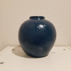 以下が含まれることがあります： 丸い形をした濃い青色のセラミックの花瓶で、エンボス加工が施されています