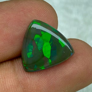 May include: A triangular green and black opal gemstone with iridescent flashes of colour.