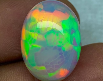 May include: A white oval opal gemstone with green, orange, and pink iridescent flashes.