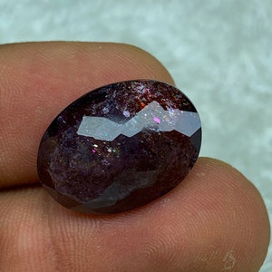 May include: A dark purple oval gemstone with iridescent sparkle and a faceted cut.