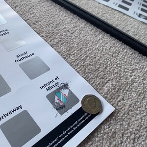 May include: A partially visible sheet with labels like "Driveway" and "Infront of Mirror" is shown. A black bar and a coin are also present. The text "Disclaimer* we do not accept responsib..." is visible. The items are on a light-colored, textured surface.