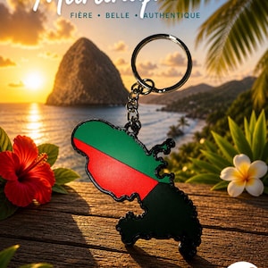 Peut inclure: Un porte-clés représentant le contour de la Martinique, aux couleurs vert, rouge et noir, avec le mot "Martinique" au-dessus. Le fond comprend un coucher de soleil sur l'océan, des fleurs et des palmiers.