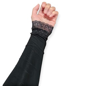 May include: Black arm warmers with a lace trim at the wrist.