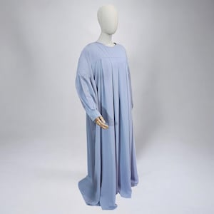 以下が含まれることがあります： 薄い青色の長袖のドレス。プリーツスカートと丸いネックラインです。