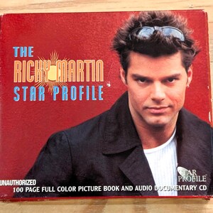 May include: A red box set titled "The Ricky Martin Star Profile" featuring a photo of Ricky Martin. The box includes text that reads "Unauthorized" and "100 Page Full Color Picture Book and Audio Documentary CD."