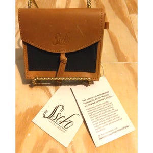 Cartera pequeña Sseko Snap de piel de vaca curtida al aceite color caramelo y negro de la India