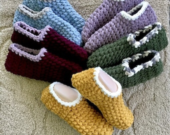 May include: Six pairs of crocheted slippers in various colors, including purple, blue, green, red, and yellow. Each pair has a white crocheted trim.