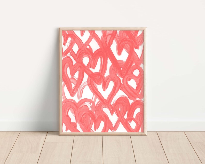 May include: A framed print featuring a white background with a pattern of pink hearts painted in a brushstroke style.