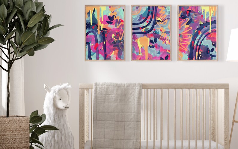 May include: Three abstract paintings in wooden frames with colorful, geometric shapes and splatters of paint in shades of pink, blue, yellow, and green.