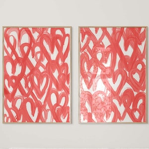 May include: Two framed prints featuring a white background with a pattern of red painted hearts.